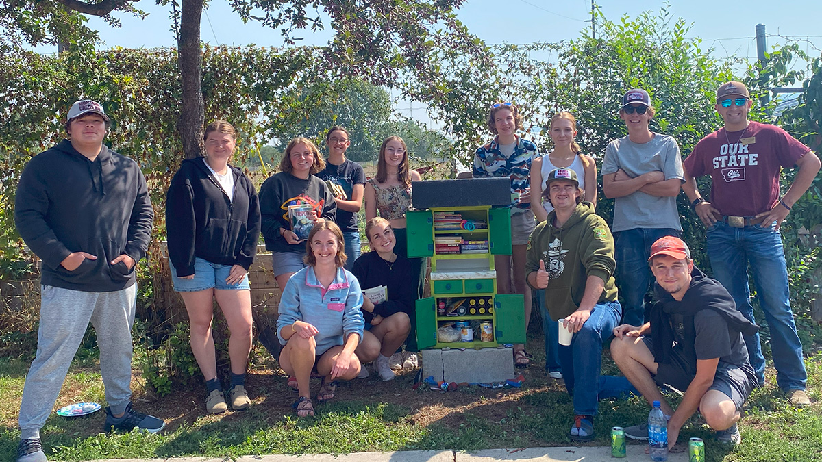 Group of UM students around little free library and pantry