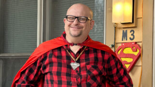 Jason Davies wearing a red superhero cape and Superman insignia
